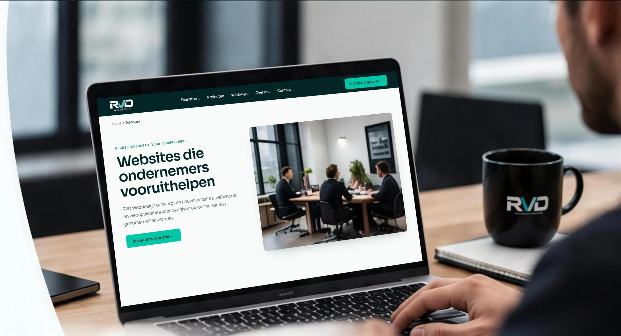 Iemand werkt op een laptop aan een website met de kop "Websites die ondernemers vooruithelpen"; ernaast een mok met het RVD-logo
