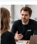 Twee mensen in gesprek aan een tafel met een laptop